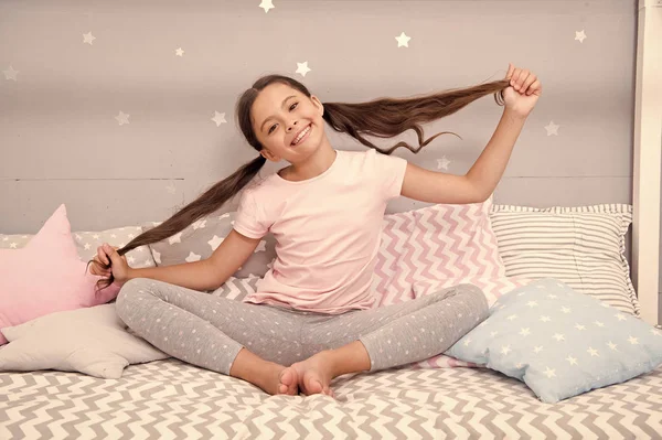 Girl child sit on bed in her bedroom. Kid prepare hair before go to bed. Girl kid long hair cute pajamas relaxing in bedroom. Time to sleep or nap. Long hair demand special care and daily combing — Stock Photo, Image