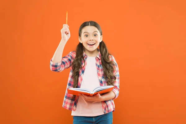 Ese libro me ha dado varias ideas. Una niñita escribiendo su idea en el diario. Un niño pequeño apuntando a un bolígrafo con idea genial. Adorable colegiala tiene idea principal de libro — Foto de Stock