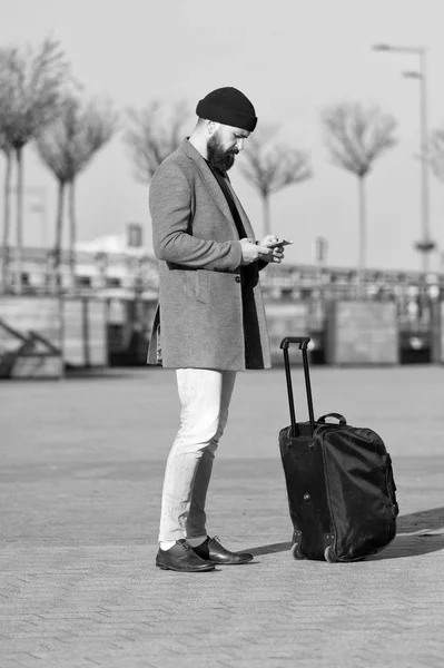 Let travel begin. Traveler with suitcase waiting transportation to airport railway station. Ready to travel. Carry travel bag. Business trip. Man bearded hipster travel with big luggage bag on wheels