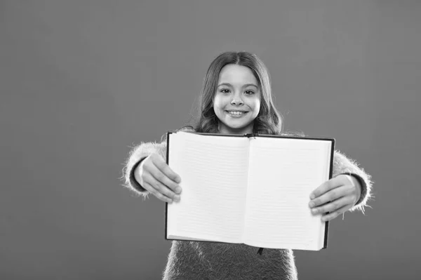 To sprawdzić. Dziewczyna hold książkę pomarańczowy tło. Dziecko Pokaż otwieranie stron książki lub Notatnik. Koncepcja książka sklep. Wolnych książek do czytania. Dzieciństwa literatury. Rozwoju i edukacji — Zdjęcie stockowe