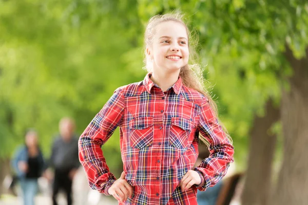 Μια διαχρονική πινελιά στυλ. Μικρό χαριτωμένο παιδί με μακρύ ξανθό στυλ μαλλιών τη θερινή ημέρα. Αξιολάτρευτο μικρό κορίτσι φορώντας καρό πουκάμισο στο στυλ του δρόμου μόδας. Το στυλ της είναι της μόδας με μια πολύχρωμη στροφή — Φωτογραφία Αρχείου
