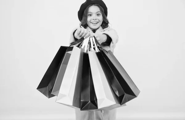 Fashionista zbožňují, nakupování. Posedlý nakupování. Roztomilé dítě dívka drží nákupní tašky na žlutém podkladu. Polovina sezóny prodej. Obchod s slevovou kartu. Získejte slevu nakupování na narozeniny nebo svátek — Stock fotografie