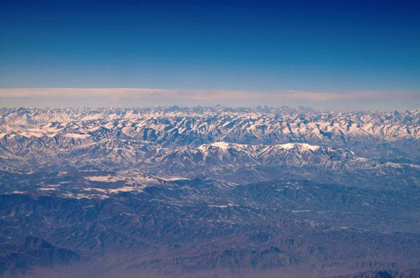 Montañas con picos nevados en el cielo azul, vista aérea. Planeta Tierra paisaje natural. Viajar alrededor del mundo. Protección del medio ambiente y ecología. El día de la Tierra es cumpleaños mundial —  Fotos de Stock