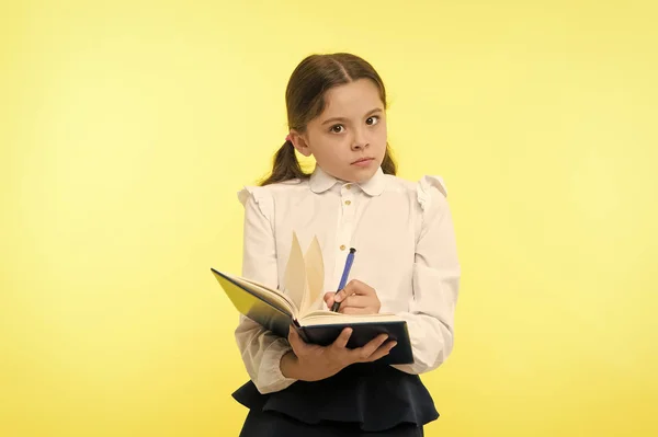 Chica linda colegiala en uniforme mantenga libro con información de fondo amarillo. Los alumnos obtienen información del libro. Los niños usan uniforme escolar prepararse para la información de la lección. Observación de información —  Fotos de Stock
