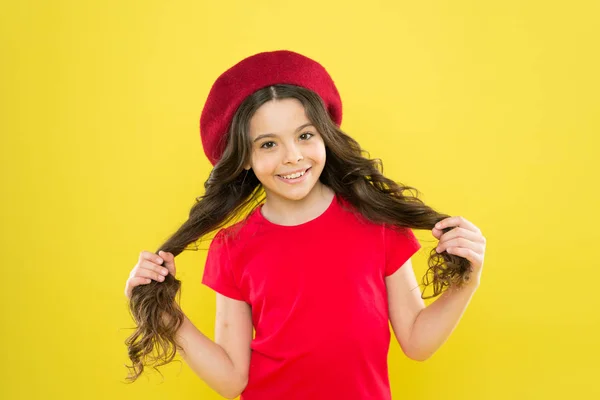 Niño parisino sobre fondo amarillo. infancia. peluquería. chica feliz con el pelo rizado largo en boina. moda de verano y belleza. Niña en sombrero de estilo francés. look de modelo de moda — Foto de Stock