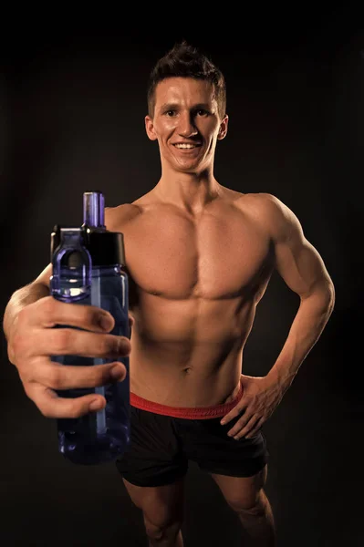 Esportista com garrafa de esporte no fundo escuro — Fotografia de Stock