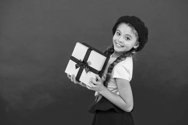 Adivinha com o que o teu filho sonha. Melhores brinquedos e presentes de Natal. Garotinha de chapéu de boina segura caixa de presente. Criança animada com o presente de desempacotamento. Pequena menina bonito recebeu pacote de presente com arco de fita — Fotografia de Stock