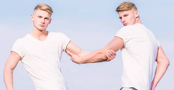 Men muscular twins brothers in white shirts sky background. Brotherhood concept. Benefits of having twin brother. Benefits and drawbacks of having identical twin brother. Friendship and support
