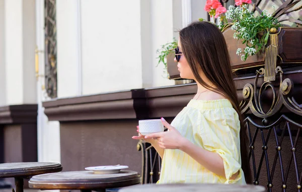 Chica disfrutar del café de la mañana. Esperando una cita. Una mujer con gafas de sol bebe café al aire libre. Chica relajarse en la taza de capuchino café. Dosis de cafeína. Café para un día lleno de energía. Hora del desayuno en la cafetería — Foto de Stock