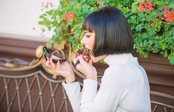 Girlish secrets concept. Woman making makeup with pocket mirror. Check if everything is right before date. Makeup concept. Girl brunette with lipstick looking in mirror check her makeup appearance