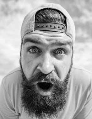 Sürpriz bir göz olması. Sakallı adam ağız moda hipster cap altında açık tutarak. Serin hippi açık. Acımasız adam uzun sakal ve bıyık. Hipster sokak moda giyim üzerinde bulutlu gökyüzü