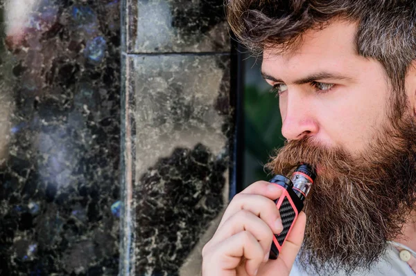 Bearded man smoking vape. Man with beard breathe out smoke. Smoking electronic cigarette. Stress relief concept. Smoking device. Man long beard relaxed with smoking habit. Clouds of flavored smoke