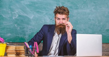 Öğretmen formal Giyim tablo sınıf kara tahta arka plan otur. Konsantre öğretmen Olgun öğretmen dikkatle dinlerken sakallı. Öğretmen dinleme cevap veya rapor. Ayrıntılara dikkat