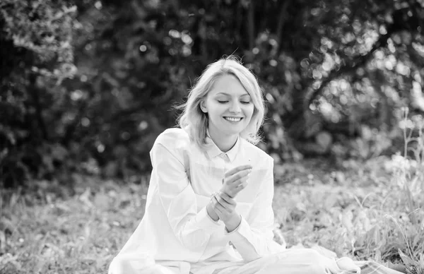 Kvinna njuta relax natur bakgrund. Damen Njut av anbud blomma doft. Kvinnlighet och ömhet. Flicka anbud blond sniff liten blomma samtidigt sitta på grönt gräs äng. Ren och anbud koncept — Stockfoto