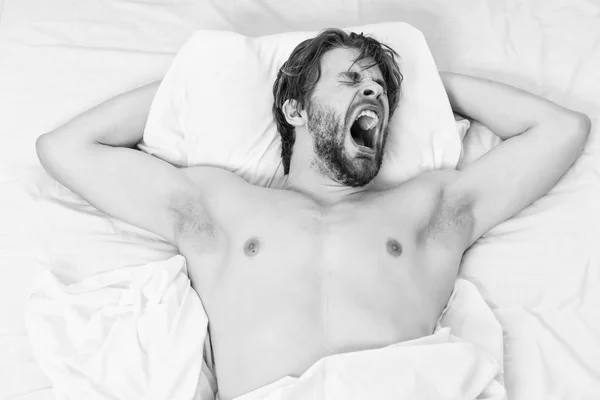 El tipo está acostado en la cama. Hombre perezoso feliz despertando en la cama levantando las manos por la mañana con sensación fresca relajado. Hombre joven cama . — Foto de Stock