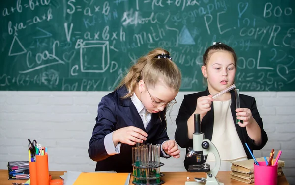 Utföra kemiska reaktioner. Grundläggande kunskaper i kemi. Gör det intressant att studera kemi. Pedagogiskt experiment koncept. Girls klasskamrater studera kemi. Mikroskop och provrör på bordet — Stockfoto