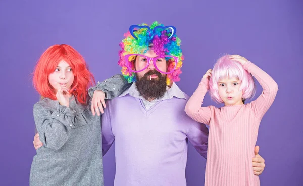 How crazy is your father. Man bearded father and kids girls wear colorful wig violet background. Friendly family wear party accessories. Best dad ever. Father hug daughters. Just for fun. Party time