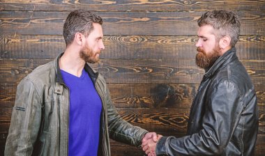 Acımasız sakallı erkekler tokalaşırken deri ceket giyer. Dostluk vahşi adamlardan. İş anlaşması onaylandı. Karşılıklı jest anlamına gelir. El sıkışma başarılı anlaşma sembolü. Kabul etti. Güçlü el sıkışma