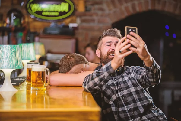 Hombre en el bar bebiendo cerveza. Tome una foto selfie para recordar la gran noche en el pub. Hombre barbudo hipster mantenga el teléfono inteligente. Tomando concepto de selfie. Comunicación en línea. Enviar selfie a amigos redes sociales —  Fotos de Stock