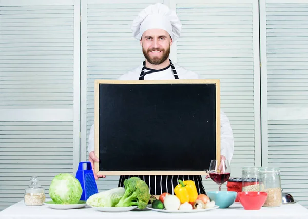 Σχολή μαγειρικής. Ο αρχιμάγειρας διδάσκει Μάστερ στη σχολή μαγειρικής. Δάσκαλος μάγειρας που δίνει μαθήματα μαγειρικής. Εκπαίδευση μαγειρικής και παρασκευής φαγητού. Ο άνθρωπος στο καπέλο σεφ κρατώντας άδειο μαυροπίνακα, αντιγραφή χώρου — Φωτογραφία Αρχείου