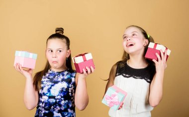 Çocuklar mutlu doğum günü hediyeleri seviyor. Alışveriş ve tatiller. Kız kardeşler hediyelerin tadını çıkarır. Çocuklar hediye kutuları bej arka plan tutun. Mutlu günler. Çocuk kızlar hediye memnun. Kızlar sevimli doğum günü kutlamak