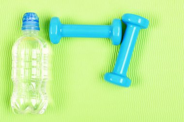 Çift mavi fitness dumbell ve şişe su.