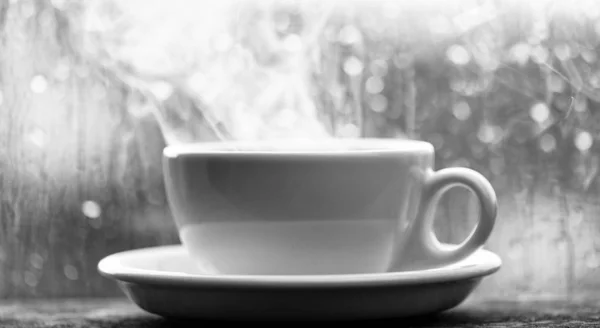 Korzystania z kawy, na deszczowy dzień. Świeże parzonej kawy w białe filiżanka lub kubek na parapecie. Kawy czas na deszczowy dzień. Mokre szybę i kubek gorącej kawy. Jesienne pochmurna pogoda lepiej z kofeiny napój — Zdjęcie stockowe