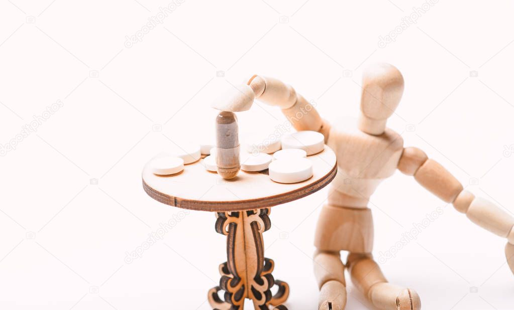 Health care and medical treatment. Pills on tiny wooden table. Medication regimen. Human wooden dummy near table with medicines. Tips tackling complex medication regimen. Take medicines after food