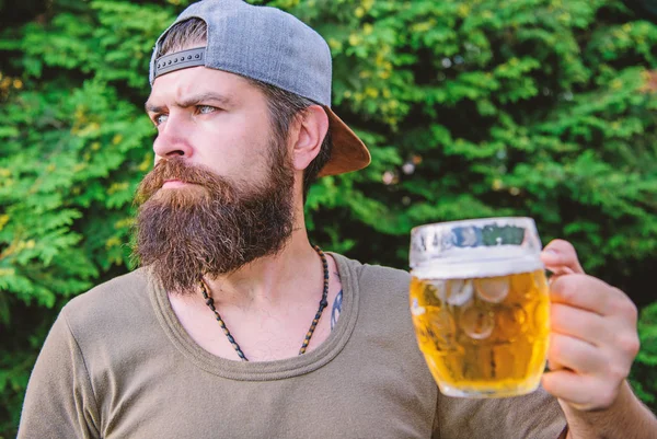 On break. Man drinker holding beer mug outdoors. Brutal hipster having craft beer on summer day. Bearded man enjoy drinking beer on nature. Beer me