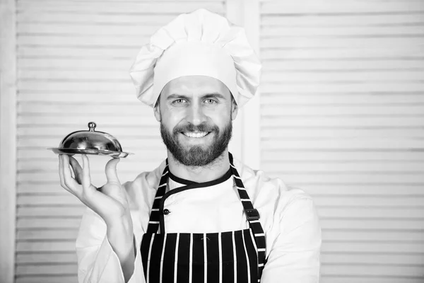 Piatto degli chef. Uomo cucinare cappello e grembiule tenere pasto coperto con coperchio. Deliziosa presentazione del pasto. Alta cucina caratterizzata preparazione meticolosa e pasto presentazione attento. Presentazione del pasto segreto — Foto Stock