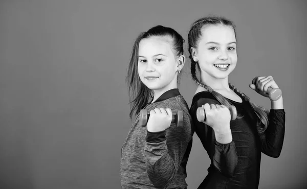 Exercices faciles avec haltère. En route pour un corps plus fort. Les filles s'entraînent avec des haltères. Débutant haltères exercices. Une éducation sportive. Les enfants tiennent haltères fond bleu. Sport pour les adolescents — Photo