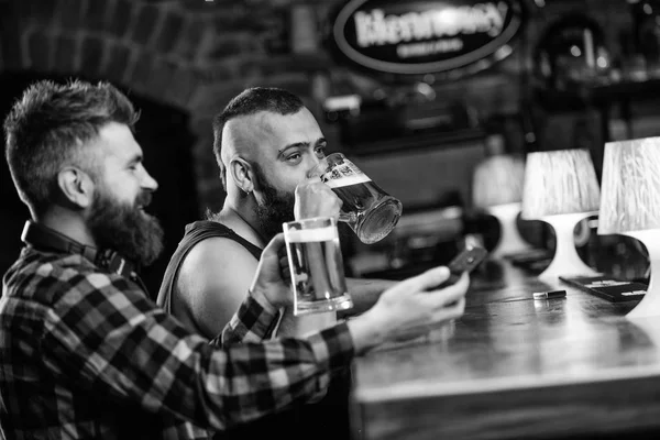 Homens a beber cerveja juntos. Hipster homem brutal bebendo cerveja com amigo no balcão do bar. Homens bêbados relaxando se divertindo. Bebidas alcoólicas. Amigos relaxando no pub com cerveja. Conceito de cerveja refrescante — Fotografia de Stock
