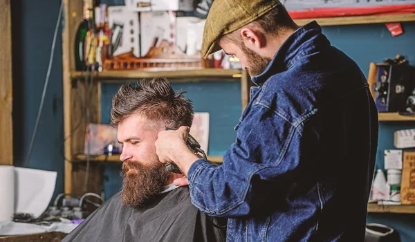 Hipster-Lifestyle-Konzept. Hipster-Klient bekommt Haarschnitt. Friseur mit Haarschneidemaschine arbeitet an Frisur für bärtigen Mann Barbershop Hintergrund. Friseur mit Haarschneidemaschine schneidet Haare an der Schläfe des Kunden — Stockfoto