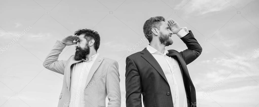 Changing course. Men formal suit managers looking at opposite directions. New business directions. Developing business direction. Businessmen bearded faces stand back to back sky background