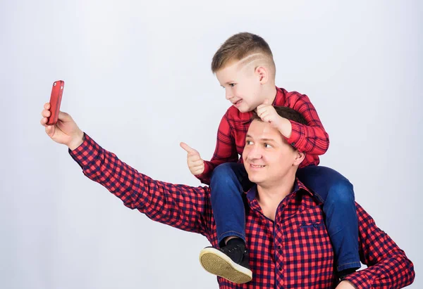 Having fun. Fathers day. Father example of noble human. Father little son red shirts family look outfit. Taking selfie with son. Child riding on dads shoulders. Happiness being father of boy