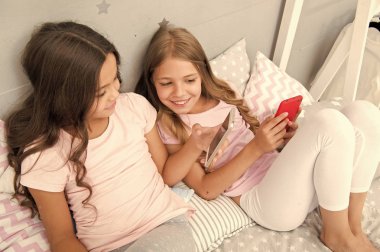 Kız çocuklar arkadaşlarım ya da kız kardeş pijama akıllı telefonlar ile meşgul giymek. Pijama çocuklarda akıllı telefonlar ile etkileşim. Çocuklar üretimi için teknolojileri. Pijama partisi fikirler. Pijama partisi için faaliyetler
