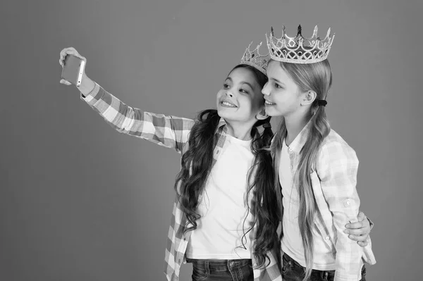 Barnen bär gyllene krona symbol prinsessan. Varningsskyltar av bortskämt barn. Undvik att höja bortskämda barn. Tjejer tar selfie foto smartphone kamera. Bortskämda barn koncept. Kräver mer uppmärksamhet — Stockfoto