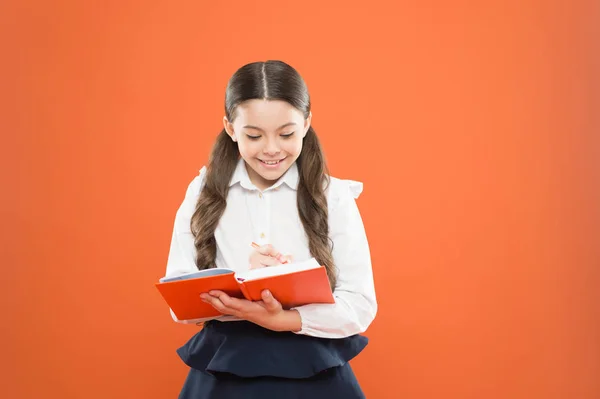 La colegiala disfruta del estudio. El uniforme de la escuela para niños tiene libro de ejercicios. Lección escolar. Niño haciendo la tarea. Tu carrera comienza aquí. Escribe ensayo o notas. Inspiración para el estudio. De vuelta a la escuela. Día del conocimiento —  Fotos de Stock