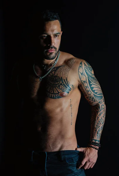 Man with tattooed arm and chest. Bearded man with strong torso. Tattoo model with sexy belly. Sportsman or athlete in fashion jeans. Bodycare or fitness and sport — Stock Photo, Image