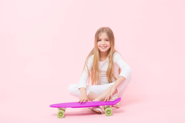 Estilo de vida ativo. Menina se divertindo com penny board fundo rosa. Criança adorável criança cabelo longo adoram passeio penny board. Feliz infância. Montar penny board e fazer truques. Menina gosta de andar de skate — Fotografia de Stock