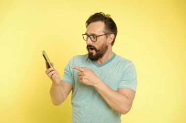 Gözlüklü adam akıllı telefonu işaret ediyor. Akıllı telefon için adam mutlu kullanıcı etkileşimli uygulama. İnsanlar online iletişimden faydalanıyor. Adamın sakallı etkileşimli mobil arayüz uygulaması