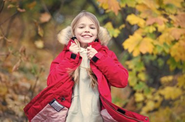 Sıcak ceketle çok rahat hissediyorum. Sıcak ceket açık yürüyüş çocuk sarı uzun saçlı. Kız kat mutlu Sonbahar Doğa Parkı tadını çıkarın. Çocuk giyim moda ceket kukuleta ile. Sonbahar giyim ve moda kavramı