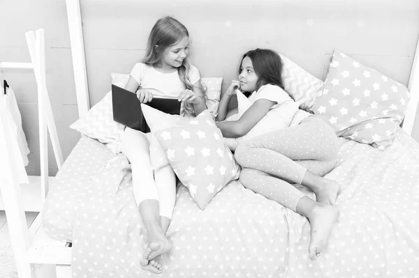 Los niños se preparan para ir a dormir. Agradable tiempo acogedor dormitorio. Las niñas de pelo largo lindo pijama relajarse leer libro. Satisfecho con el libro final feliz. Su libro favorito. niñas hermanas laico cama leer libro juntos — Foto de Stock