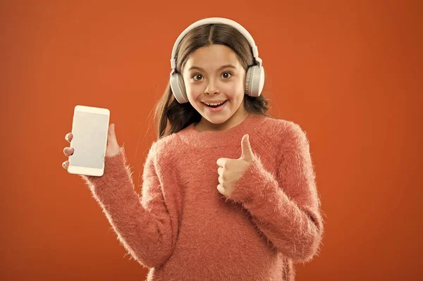 Dziecko dziewczynka słuchać muzyki nowoczesne słuchawki i smartphone. Pobierz muzyka subskrypcja dla rodzin z dziećmi. Dostęp do milionów utworów. Ciesz się koncepcja muzyki. Najlepsze aplikacje muzyczne, które zasługują na słuchać. Słuchaj za darmo — Zdjęcie stockowe