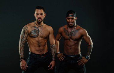 Maço kas dövmeli torsolar ile çekici, koyu arka plan bak. Atletler çıplak kas sandıkları ile kendine güvenen yüzleri. Seksi kas torsolar ile çocuklar sporcular. Erkeklik kavramı