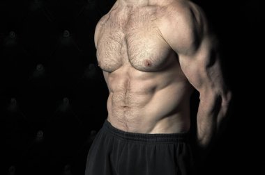 Güçlü adam atletik vücut geliştiricisi. Tanınmayan hiç yüz portre. Çıplak gövde, kas vücut. Güçlü göğüs ve omuz kasları. Siyah arka plan üzerine ateş stüdyo vücut geliştirme kavramı gösterir