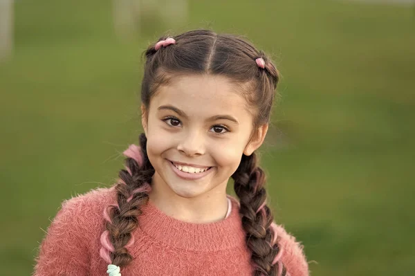 Menina pequena com rosto bonito relaxante ao ar livre. Belo penteado. Rosto sorridente com olhos brilhantes. Desfrutando do tempo e da natureza na floresta. Fundo verde. Humor positivo de menina menina — Fotografia de Stock