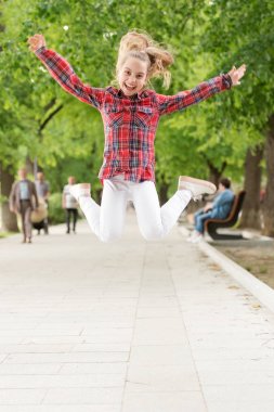 Yorulmak bilmez ve enerjik bir aktivite. Küçük bir çocuk fiziksel aktivite için normal bir şekilde atlıyor. Aktif çocuk yaz parkında oyun oynamaktan zevk alıyor. Çocukken açık hava aktivitesi için giyinmiş küçük bir çocuk.