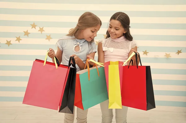 Compras com conceito de melhor amigo. As raparigas gostam de fazer compras. Crianças felizes meninas pequenas segurar sacos de compras. Desfrute de compras com melhor amigo ou irmã. Felicidade feminina. Crianças felizes transportar pacotes de grupo — Fotografia de Stock