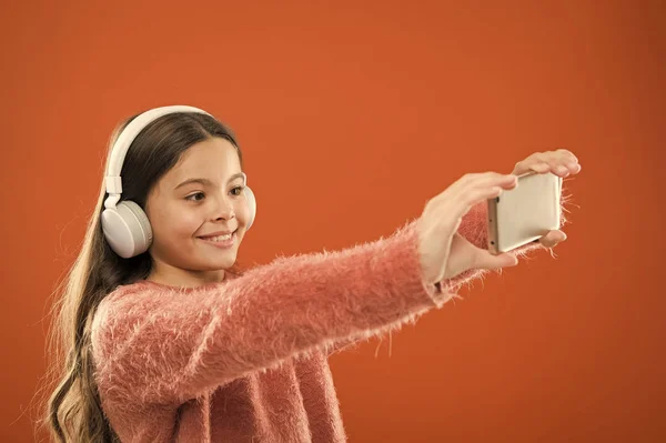 Słuchaj za darmo. Aplikacja mobilna dla nastolatków. Dziecko dziewczynka słuchać muzyki nowoczesne słuchawki i smartfona biorąc selfie. Uzyskaj subskrypcję music. Ciesz się koncepcja muzyki. Najlepsze aplikacje muzyczne, które zasługują na słuchanie — Zdjęcie stockowe
